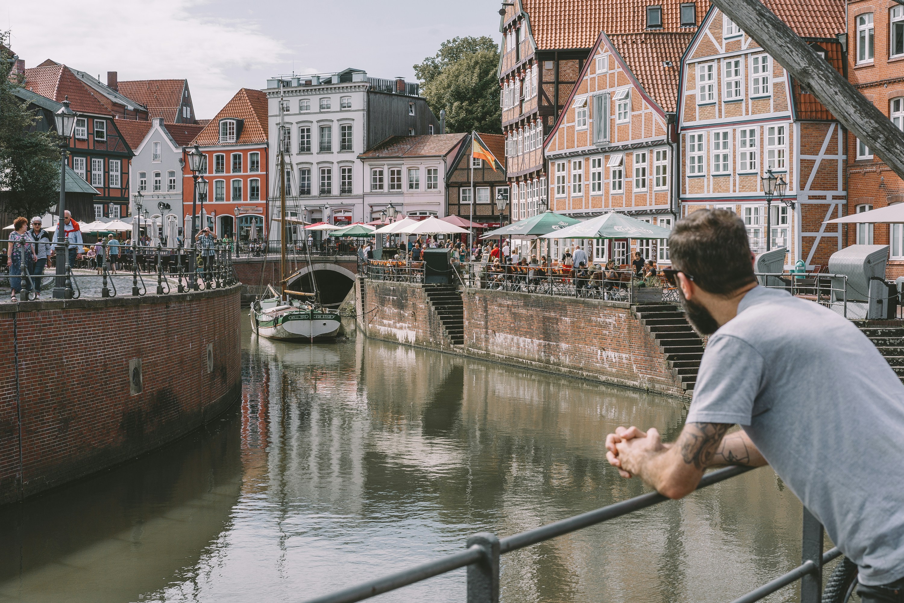 A man leaning on a railing over a river with buildings on either side ...