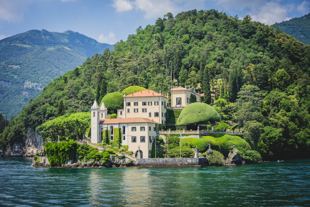 a house on a hill by a body of water with Villa del Balbianello in the background