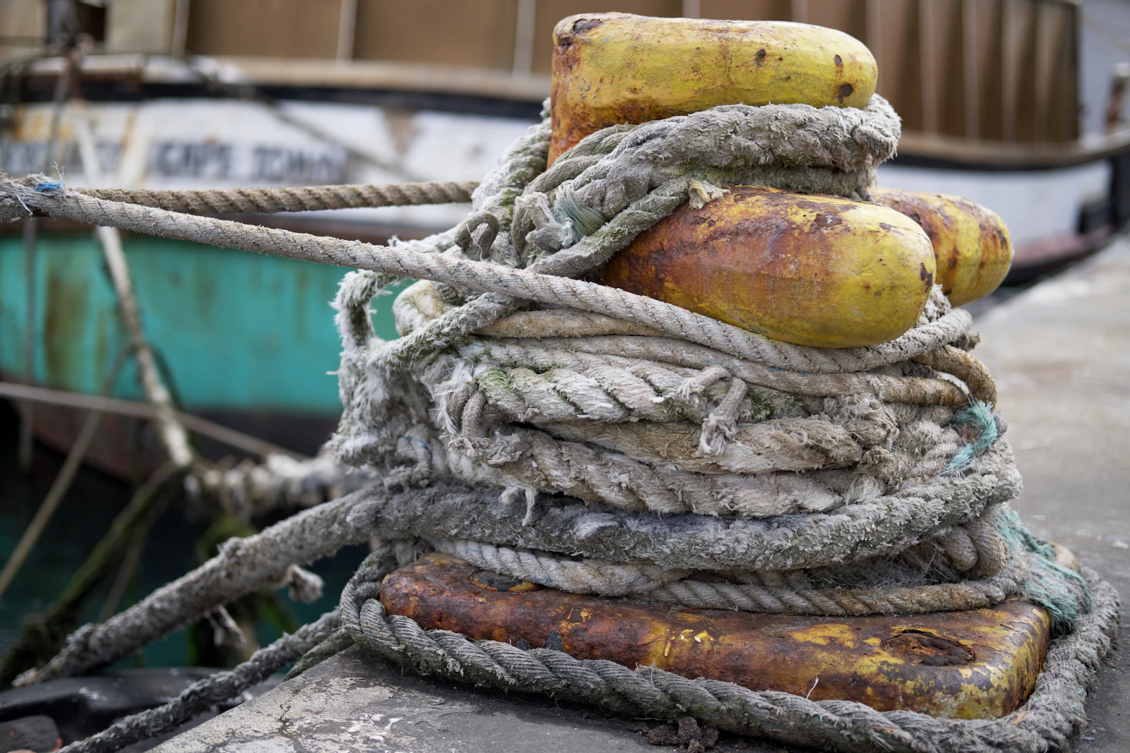 Thick mooring rope wound around a yellow bollard on a quay