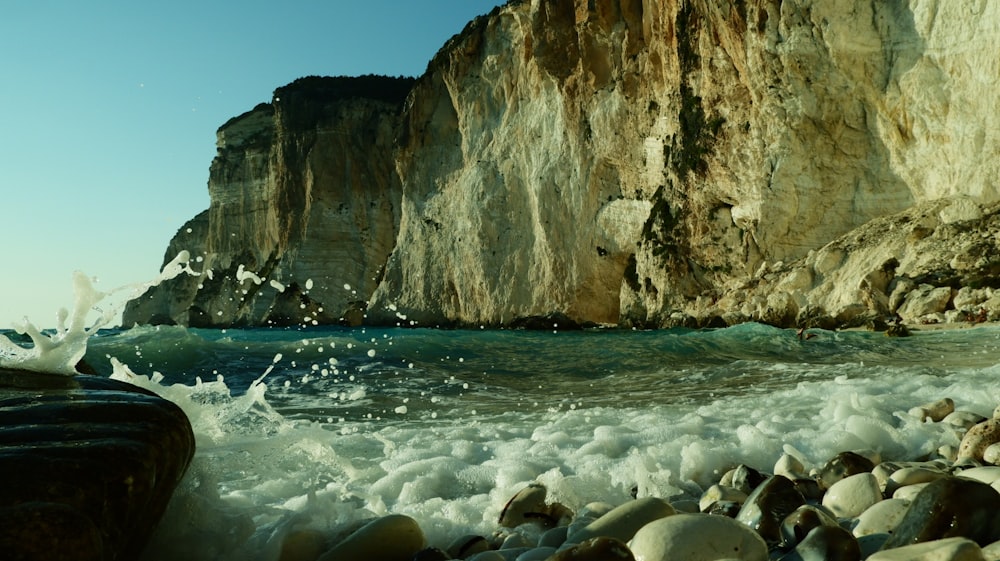 a rocky beach with a large rock formation in the background