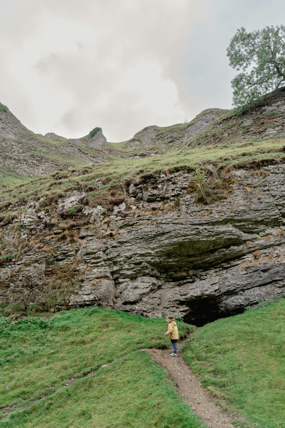 a person walking on a path next to a rocky cliff