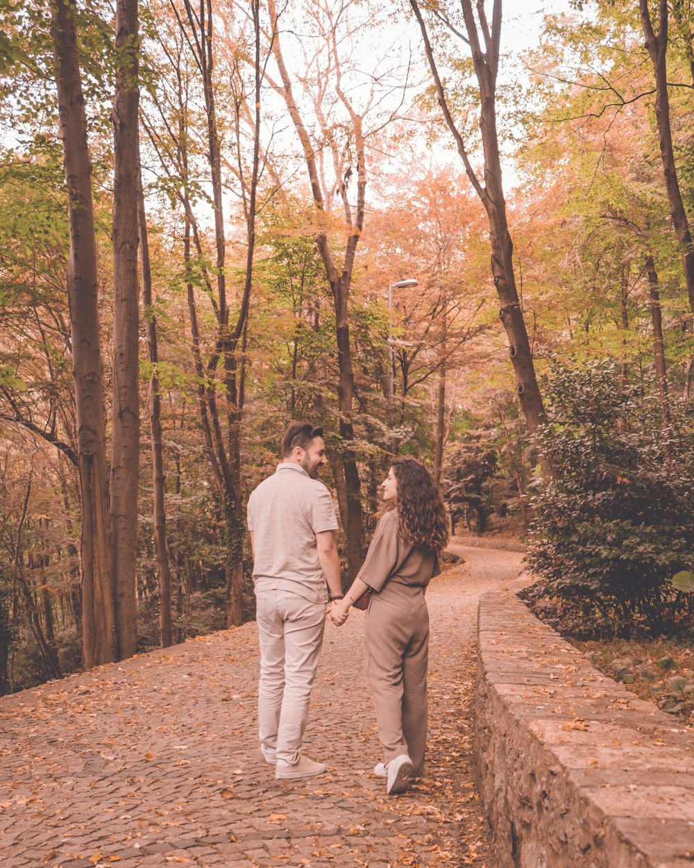 a man and woman walking on a path in the woods