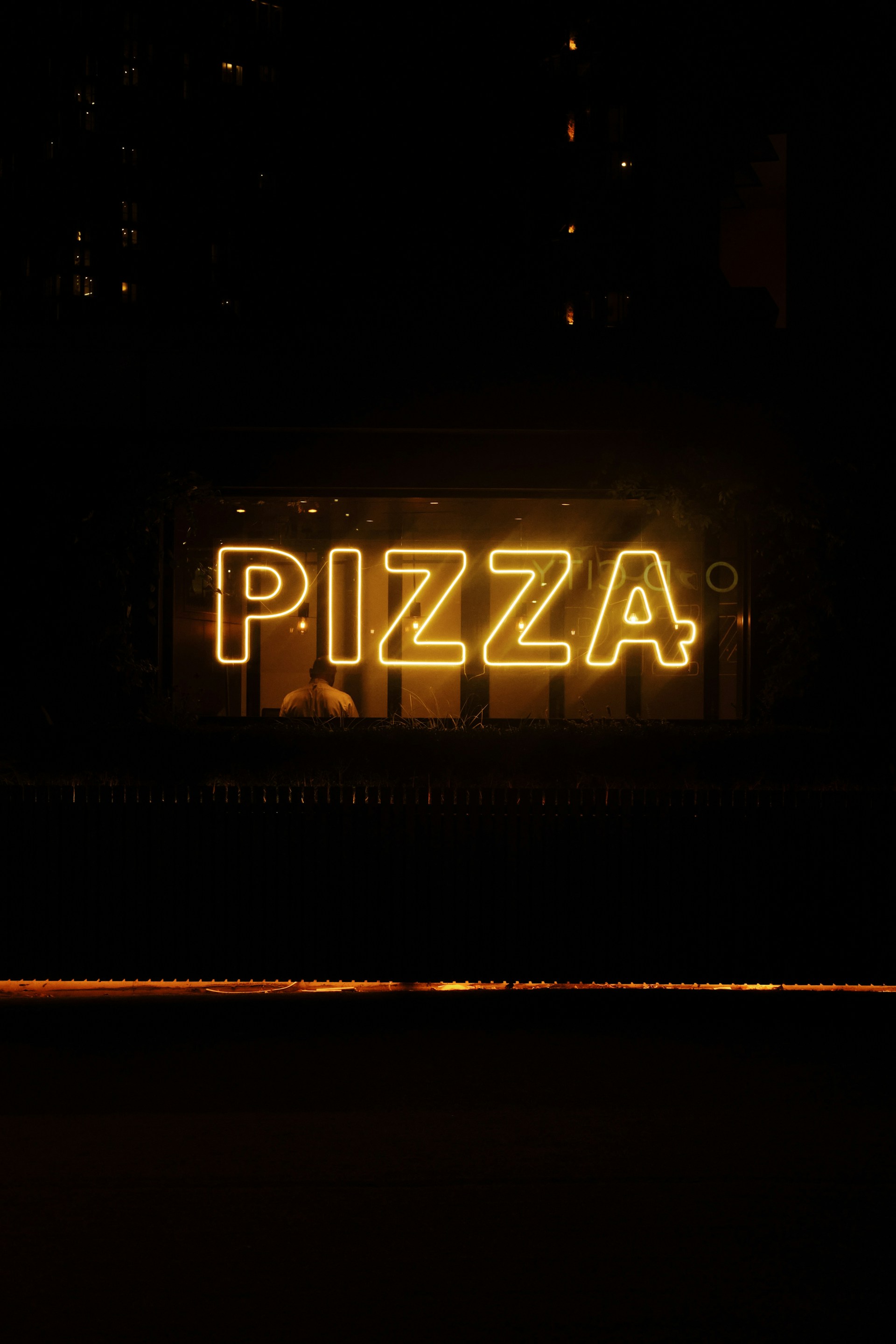 a person standing in front of a sign with lights in the background