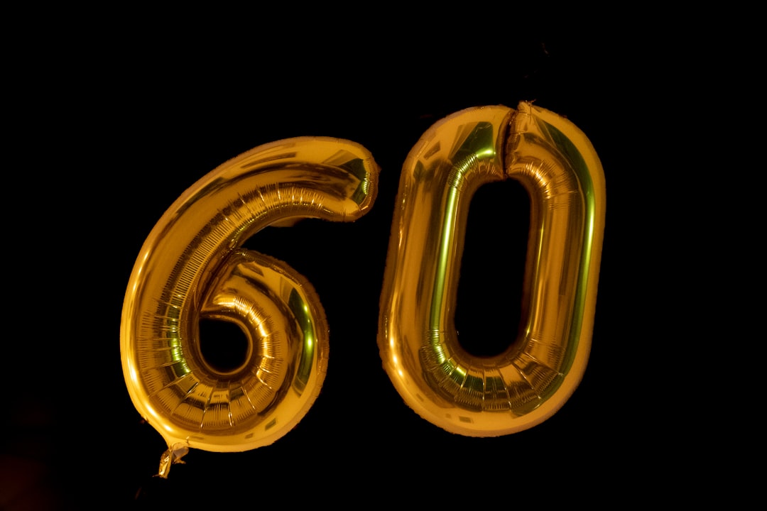 Gold 60th birthday balloons on a black background.