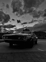 A vintage car with circus tents in the background under a dusky sky.