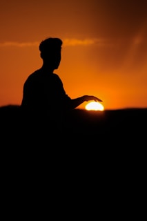 a silhouette of a person with a sunset in the background
