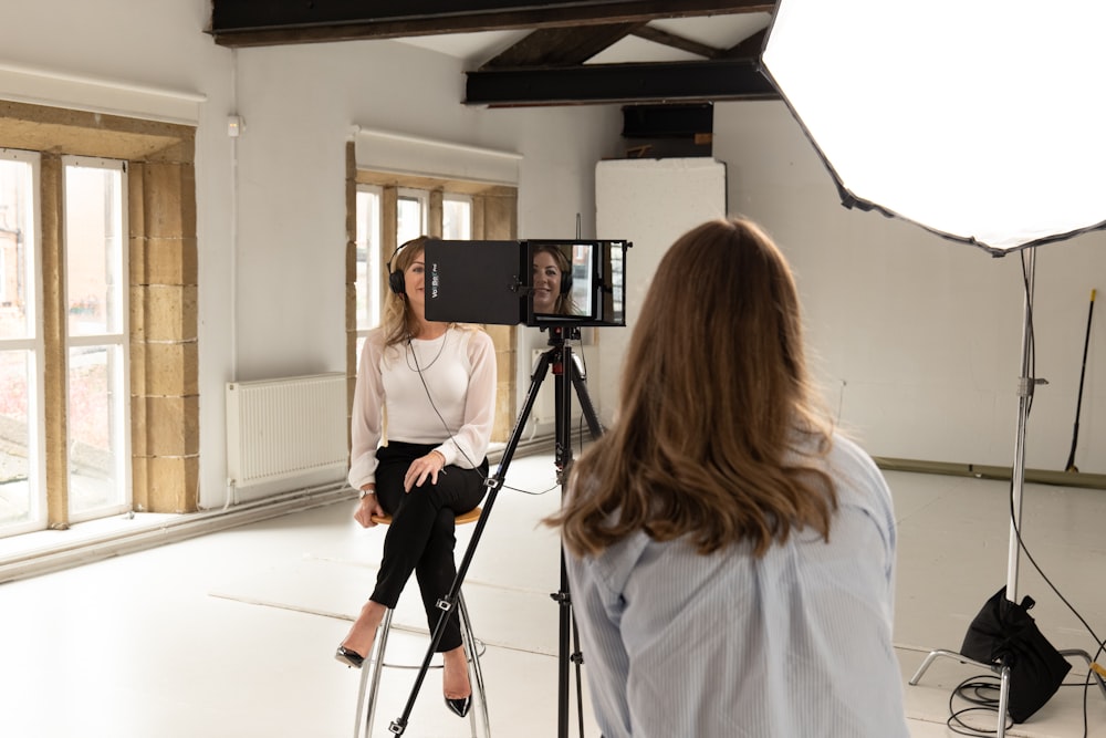 a person standing next to a person sitting on a tripod