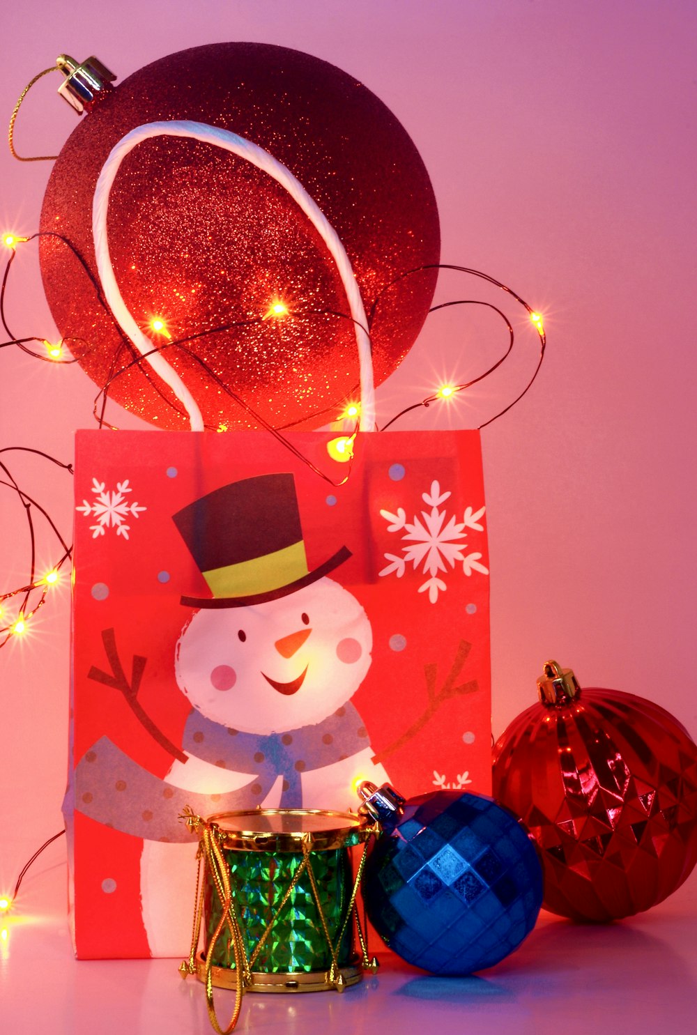 um pequeno boneco de neve em um chapéu de Natal e um presente