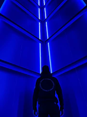 A sleek futuristic door glowing with neon blue light in a dark corridor.