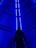 A person stands in front of a futuristic, illuminated blue corridor. The walls and ceiling are lined with bright blue LED lights, casting a vivid glow throughout the space.