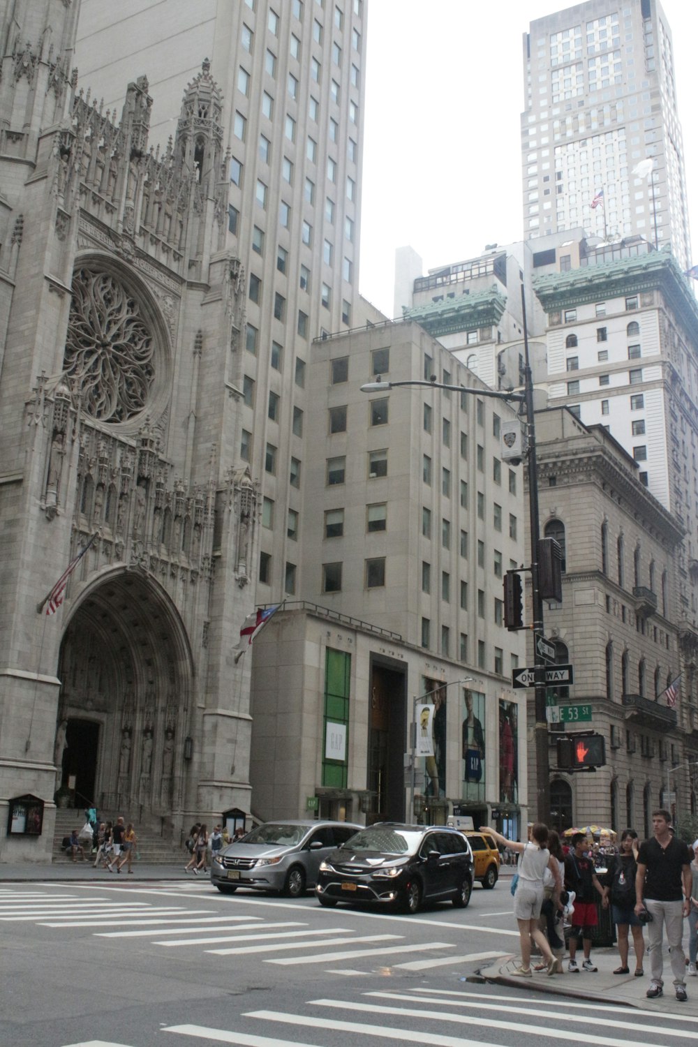 a street with cars and people on it next to a large stone building