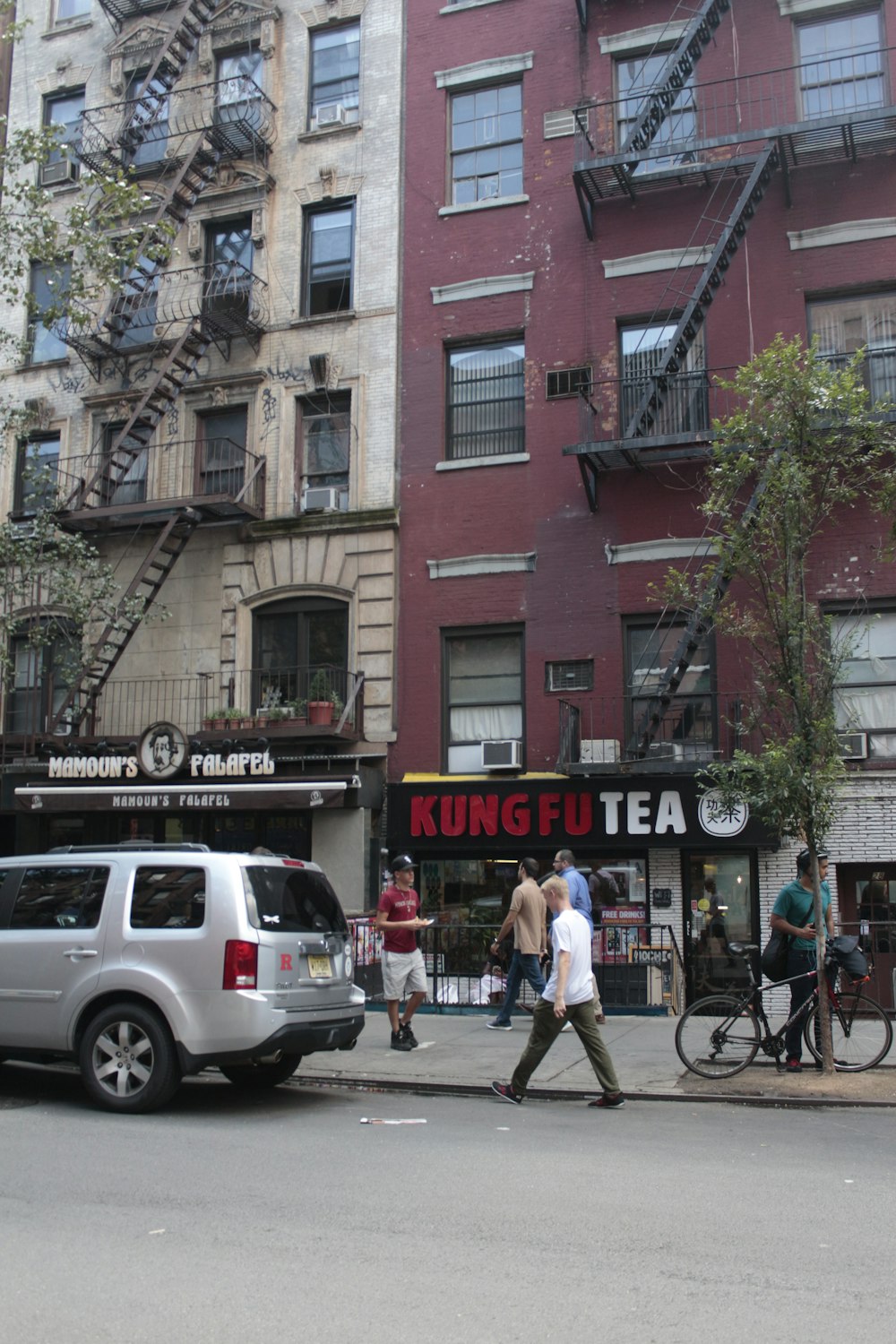 a group of people walking on the sidewalk next to a building