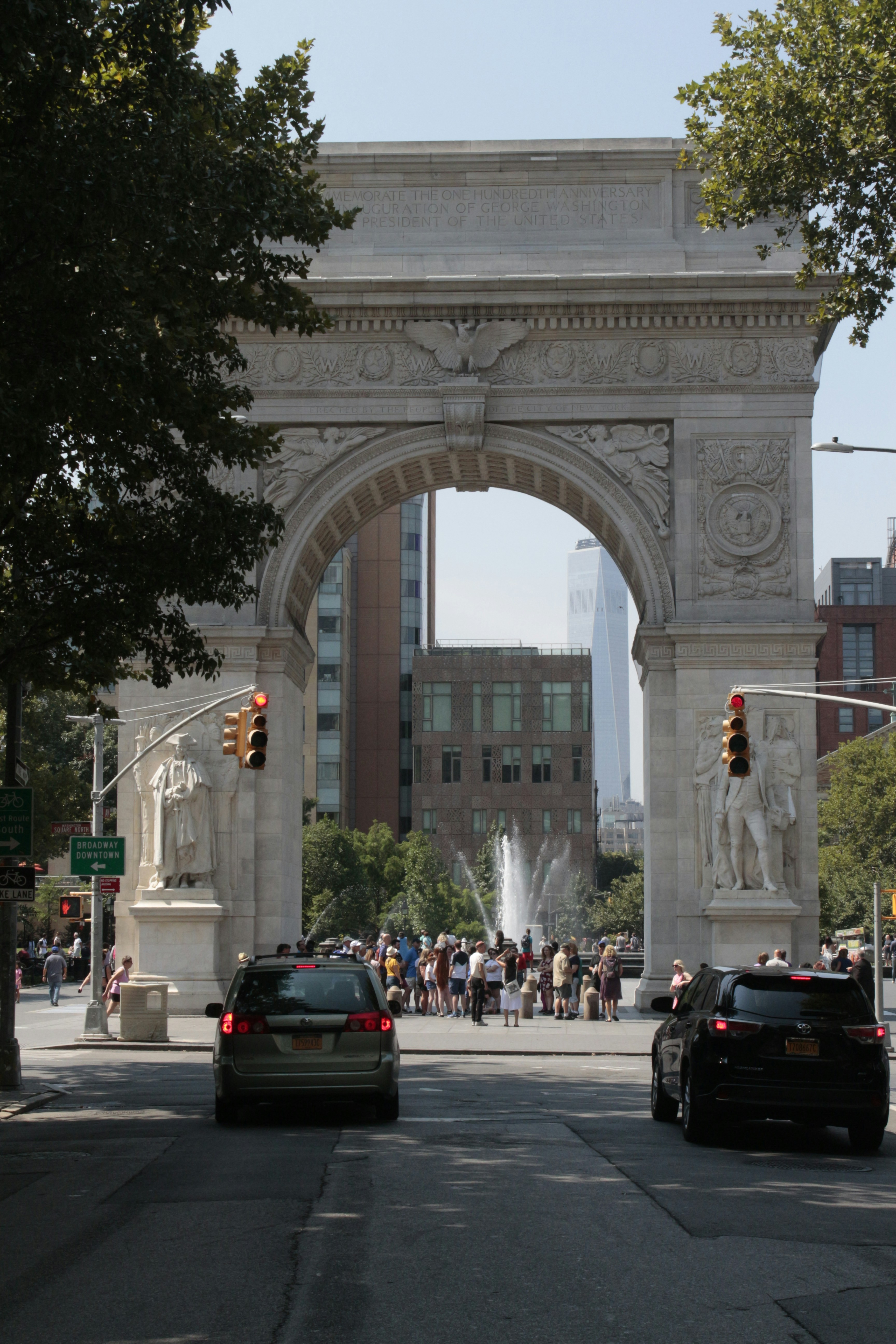 A large stone arch with a crowd of people below with Washington Square Park in the background