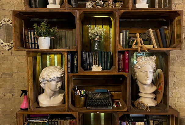 Rustic wooden shelf filled with books and plants against a white wall