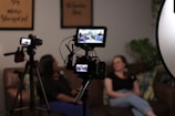 a person sitting on a couch next to a camera and a television