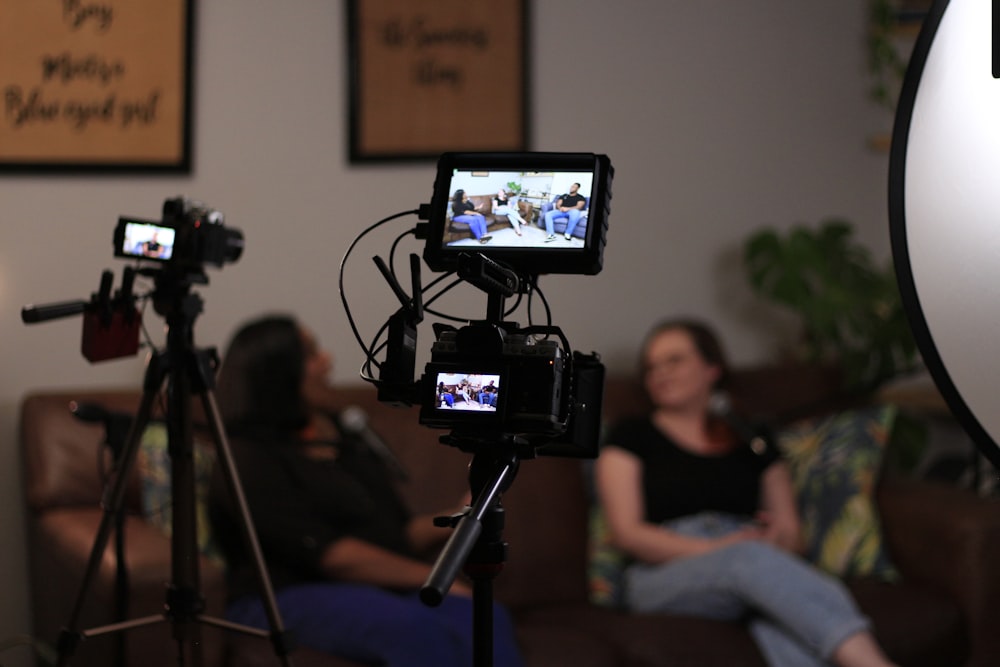 a person sitting on a couch next to a camera and a television