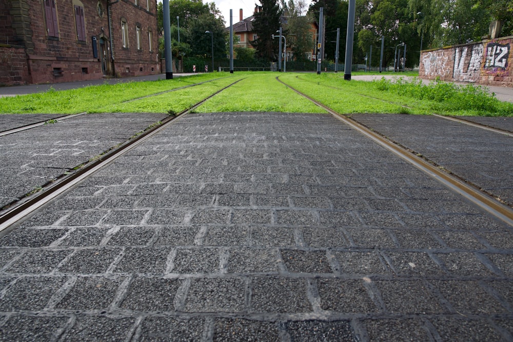a brick road with a brick wall and grass and trees on either side