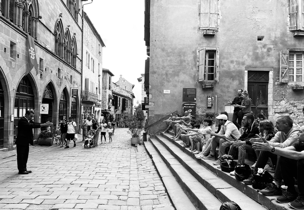 a group of people sitting on a sidewalk in a city