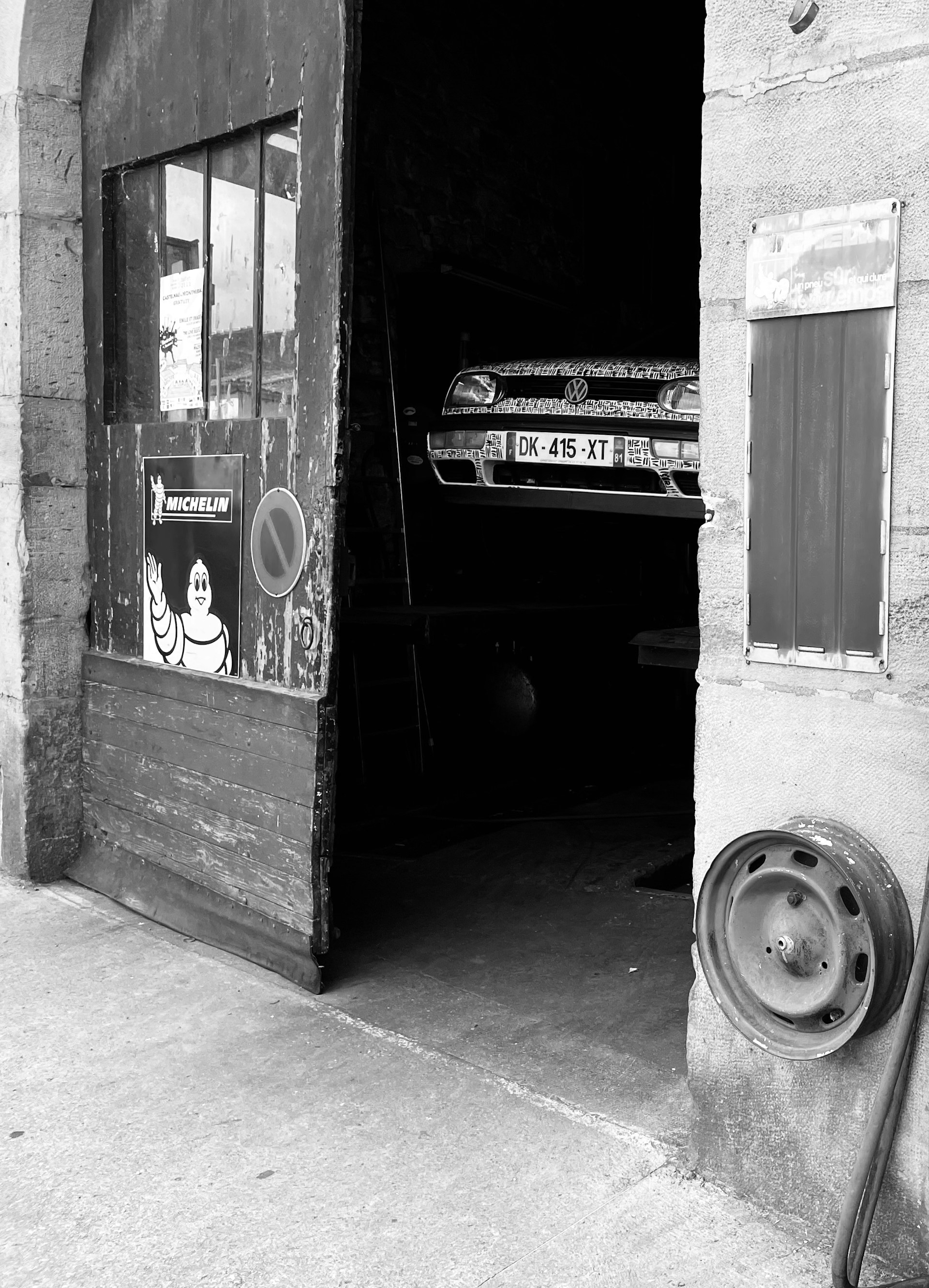 a black and white photo of a car parked in front of a building