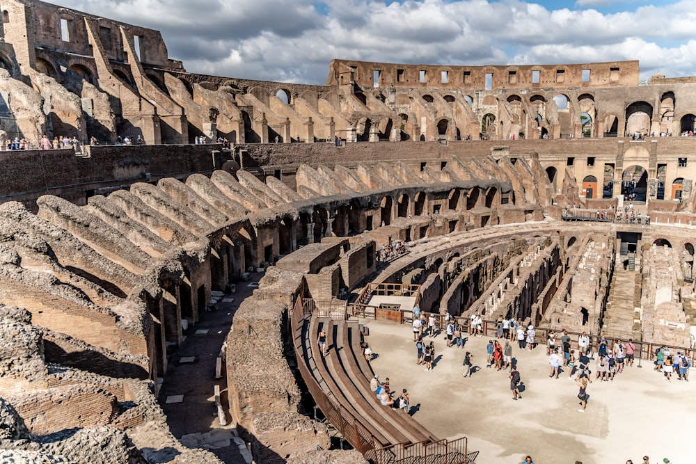 a large ancient building with many people with Colosseum in the background