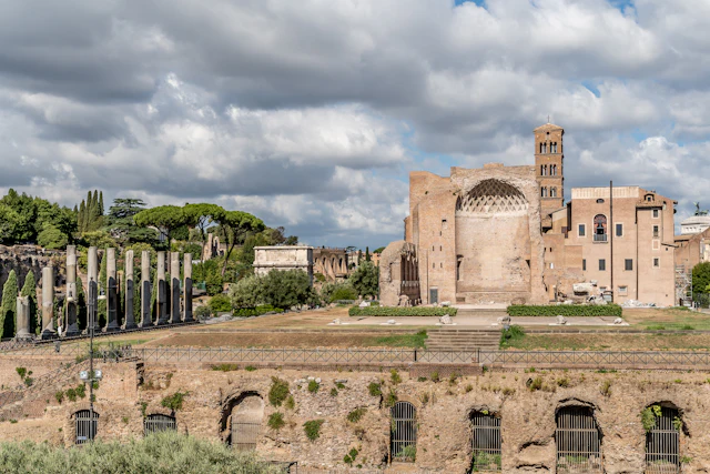 Ancient ruins and cypress trees on Palatine Hill with a domed church and bell tower in the background
