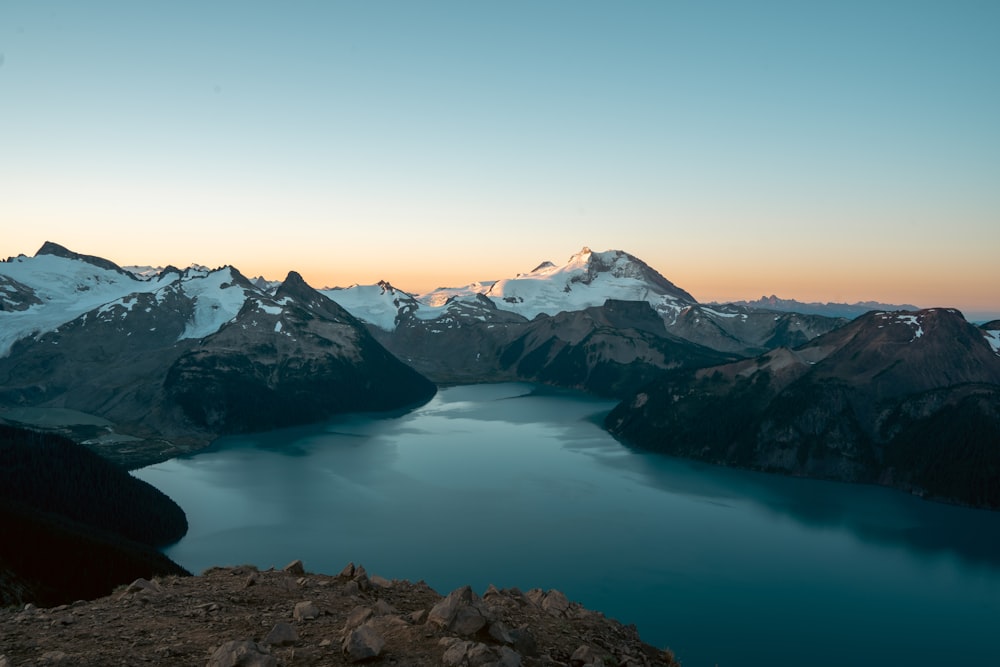 a body of water with snow covered mountains in the background