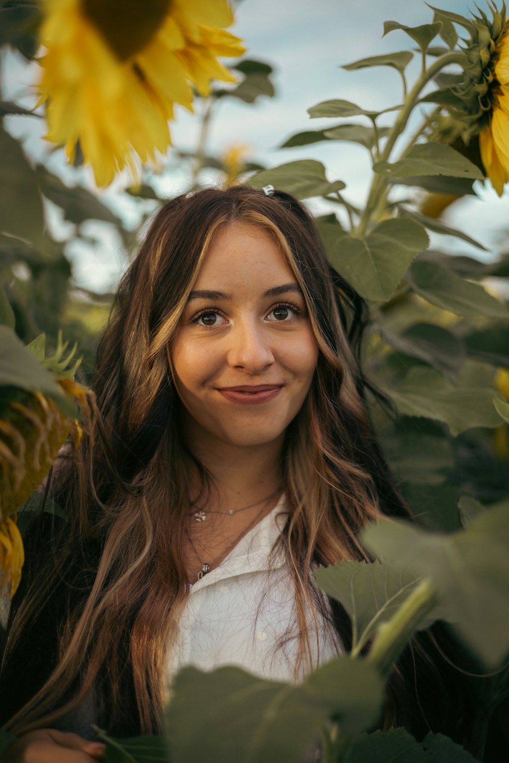 黄色い花を持つ木の前で微笑む女性