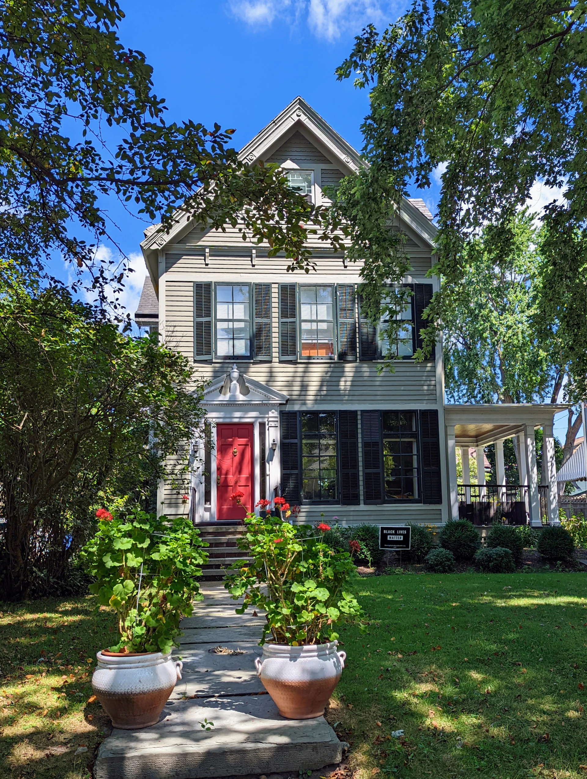 The exterior of a charming house with a newly painted deep red front door and crisp white trim, highlighting Coloris' exterior expertise.