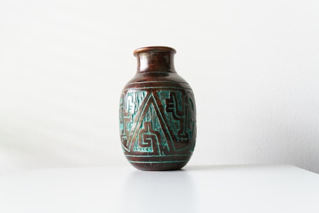Close-up of a handcrafted ceramic vase with intricate patterns on a wooden table.