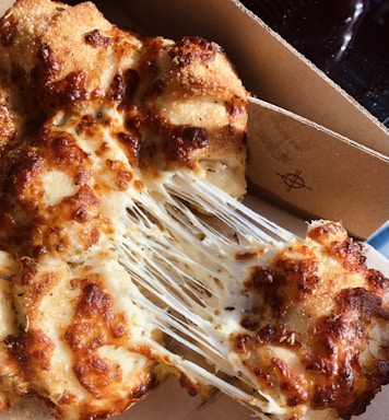 A vibrant photo showing a cheese burst pizza with melted cheese stretching as a slice is lifted.