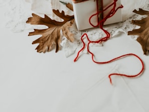 Hands wrapping a gift box containing lewallens dinnerware, tied with natural twine