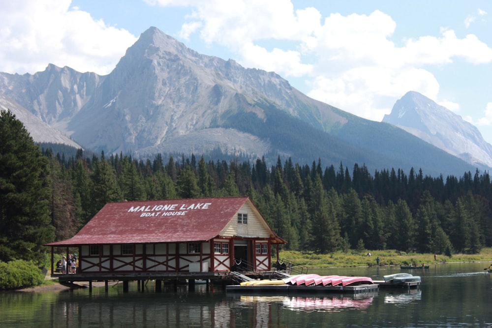 a building on a dock by a lake with mountains in the background