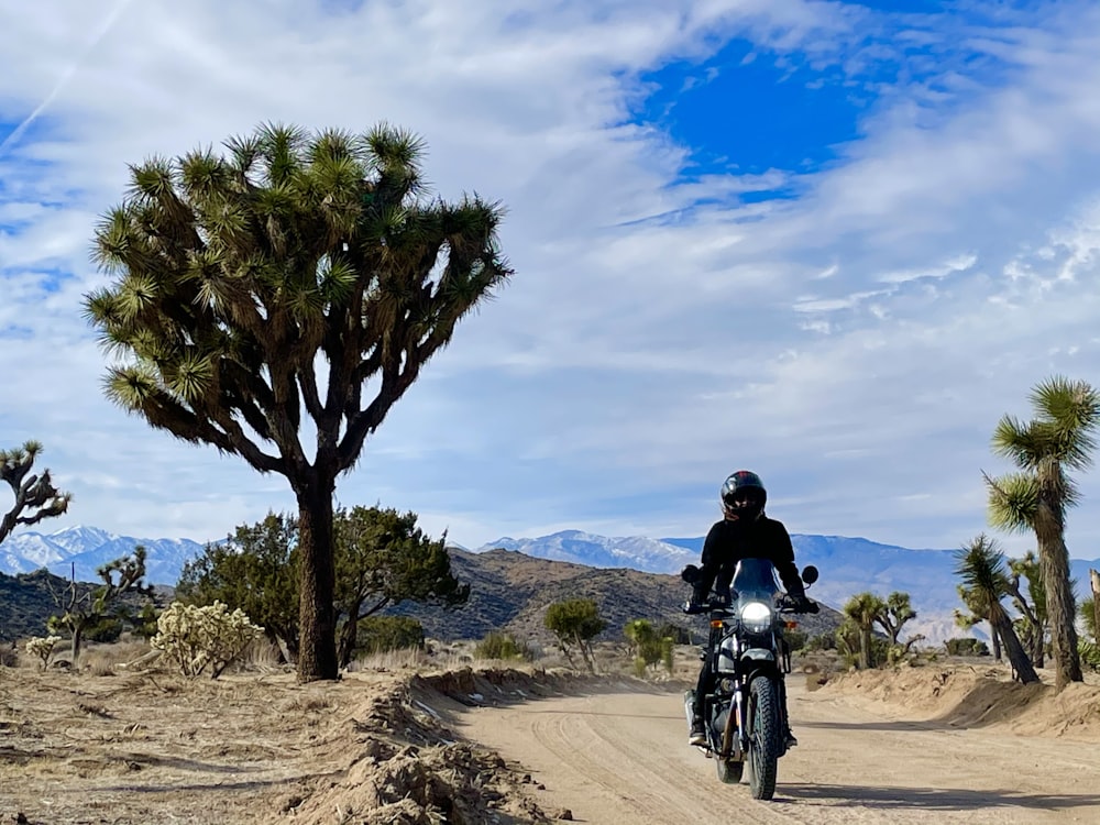 a man riding a motorcycle on a dirt road