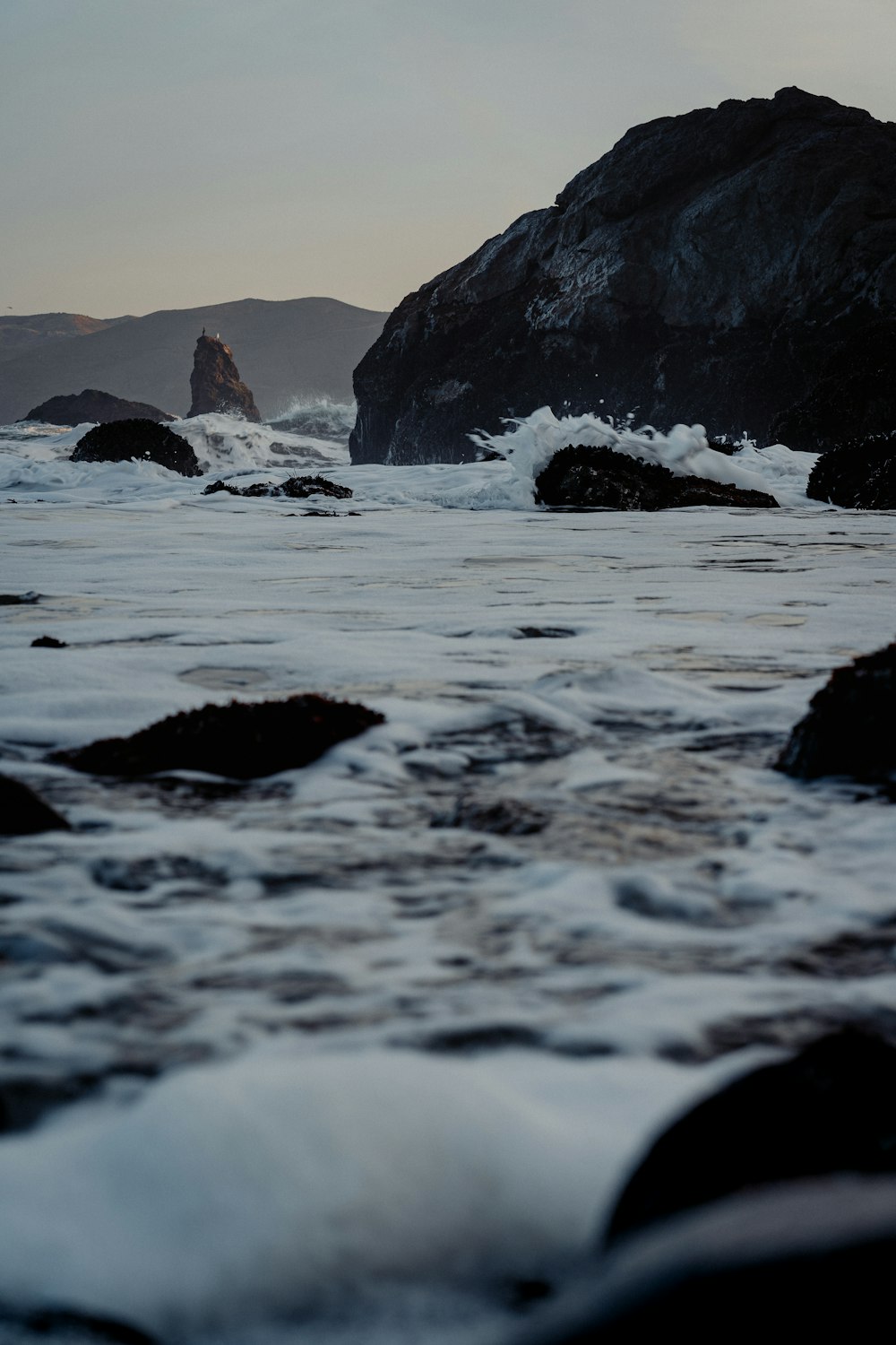 a body of water with rocks in it and a large rock in the background