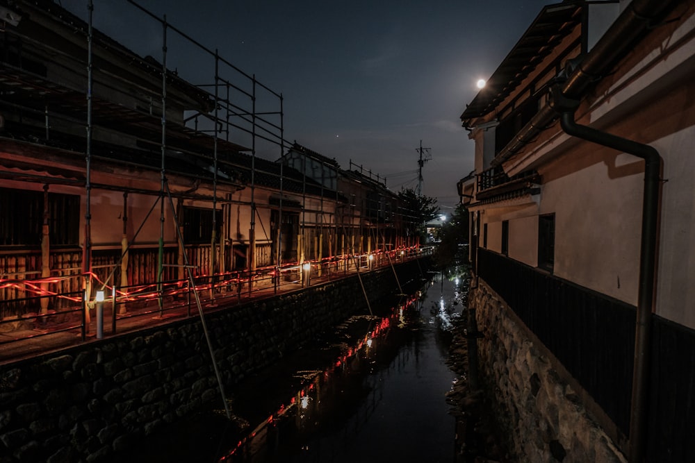 a canal with a row of metal structures and a building with a bridge