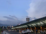 A sleek VIP shuttle waiting outside a modern airport terminal at sunset.