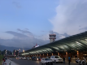 A comfortable taxi parked outside a modern airport terminal at sunset.