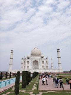 a large white building with a dome and towers with Taj Mahal in the background
