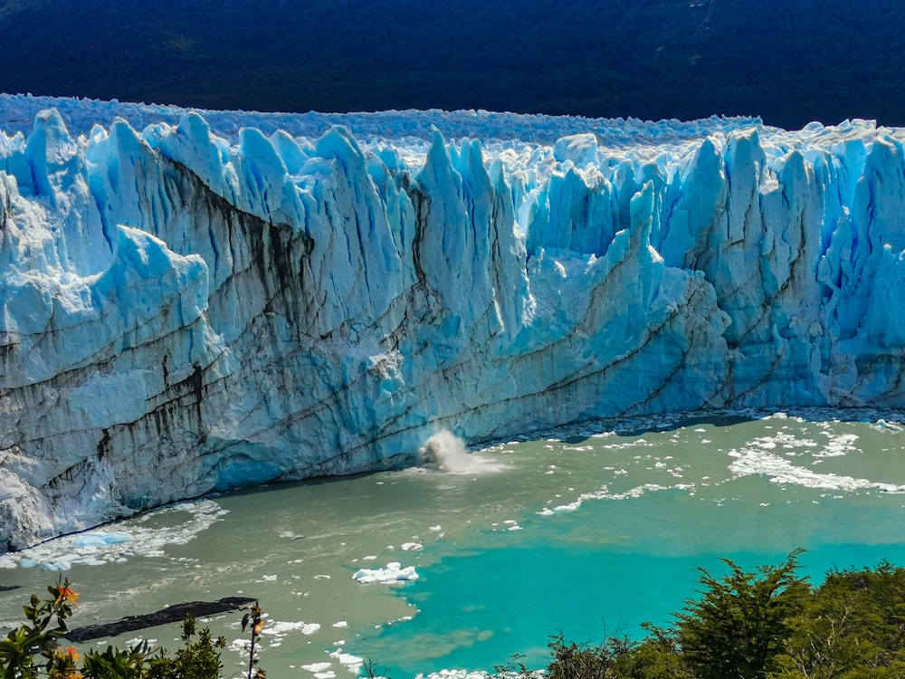 a large glacier with water below with Perito Moreno Glacier in the background