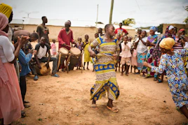 A vibrant gathering of people singing and dancing together outdoors, embodying communal rhythm and joy.