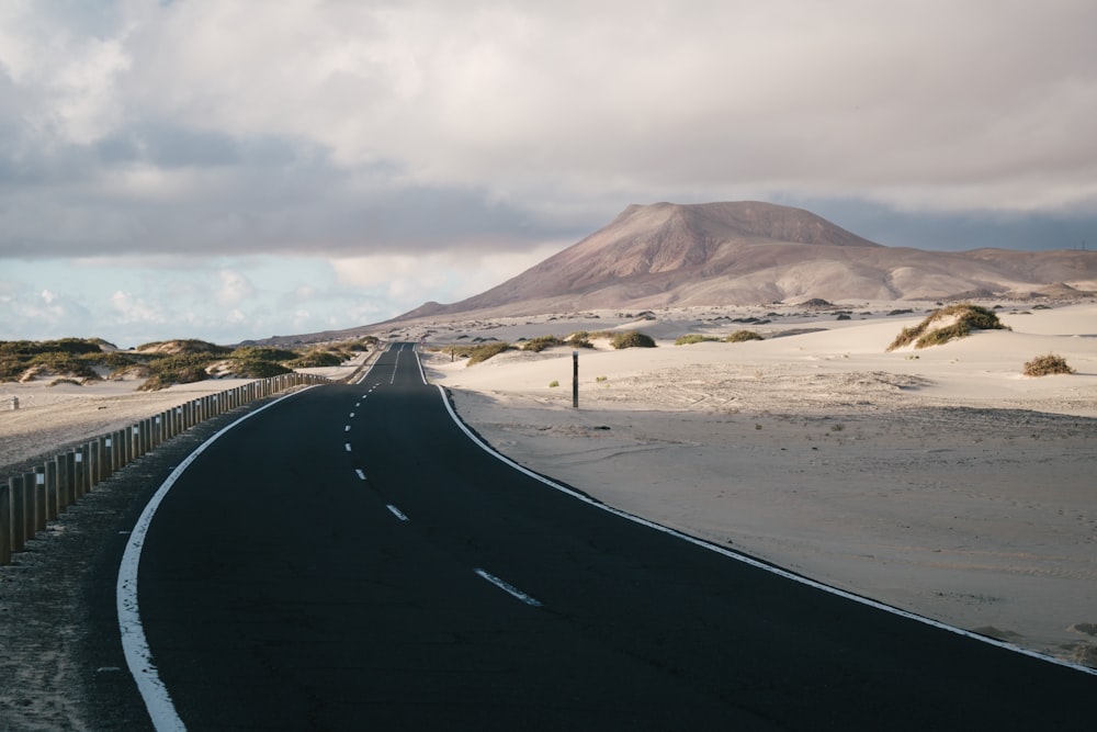 a road with sand and hills in the background