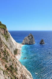 a rocky cliff next to a body of water