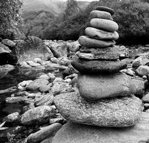Close-up of smooth stones stacked beside gently flowing water in a tranquil setting.