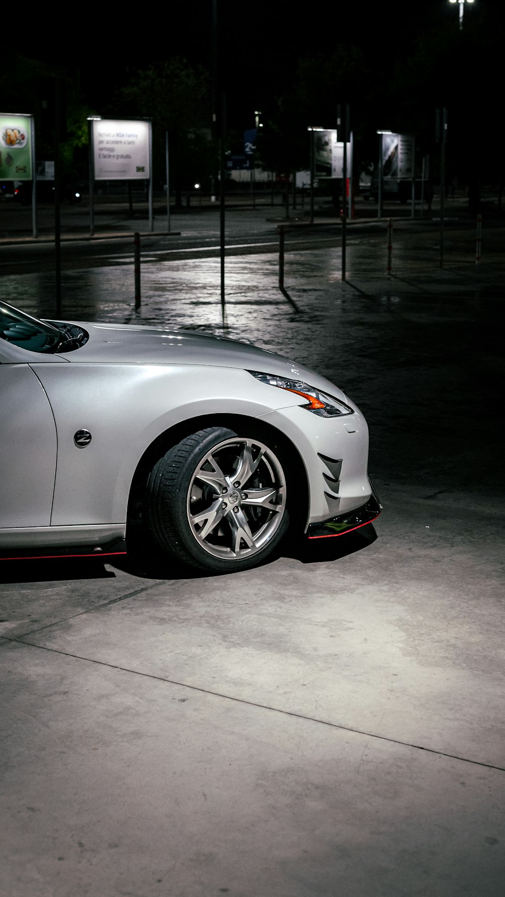 a white sports car parked on a wet street at night