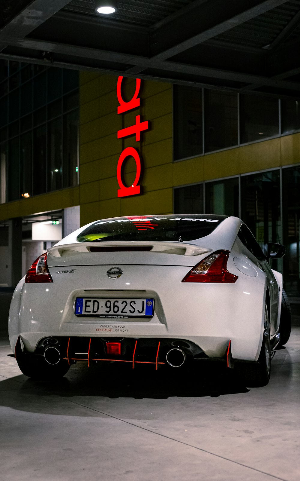 a white sports car in front of a building with a sign on it