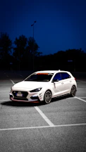 a white car parked in a parking lot at night