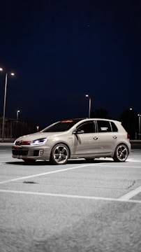 a silver car parked in a parking lot at night