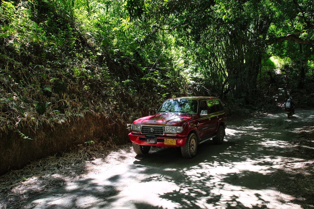 Une voiture rouge sur un chemin de terre