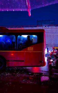 Night shot of a red and white VIP transfer vehicle illuminated by city lights