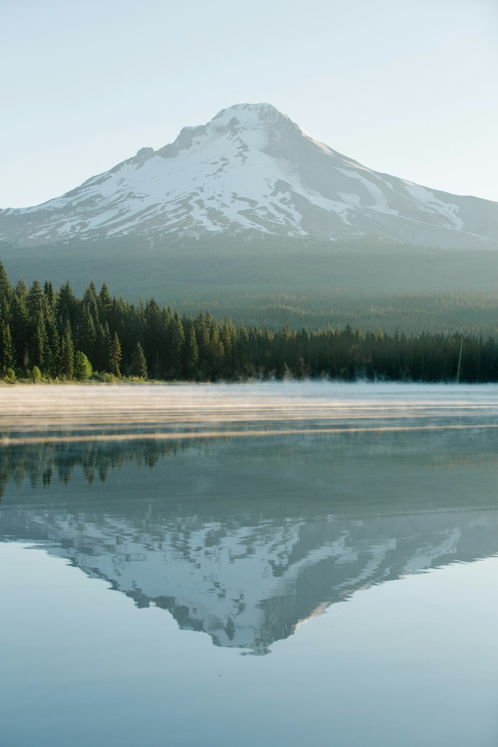 a snowy mountain behind a lake